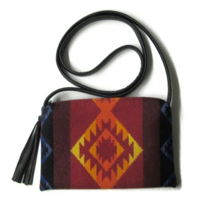 May include: A small, red, orange, yellow, and blue patterned crossbody bag with a black leather strap and tassel.