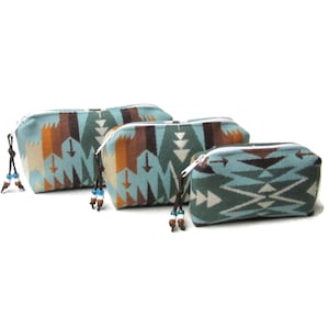 May include: Four zippered cosmetic bags in varying sizes. The bags feature a turquoise, brown, orange, and white geometric pattern. Each bag has a white zipper and a beaded pull. The bags are arranged in a row.