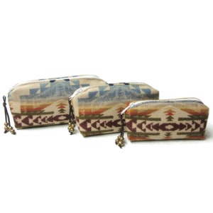 May include: Three zippered pouches with a southwestern pattern in shades of brown, beige, blue, and red. The pouches are lined up in order of size, with the largest pouch on the left and the smallest pouch on the right.