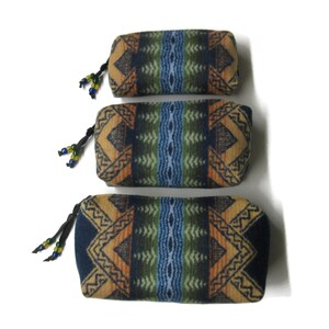 May include: Three cylindrical fabric pouches with a geometric pattern in shades of blue, green, orange, and brown. The pouches have a drawstring closure and are decorated with beads.