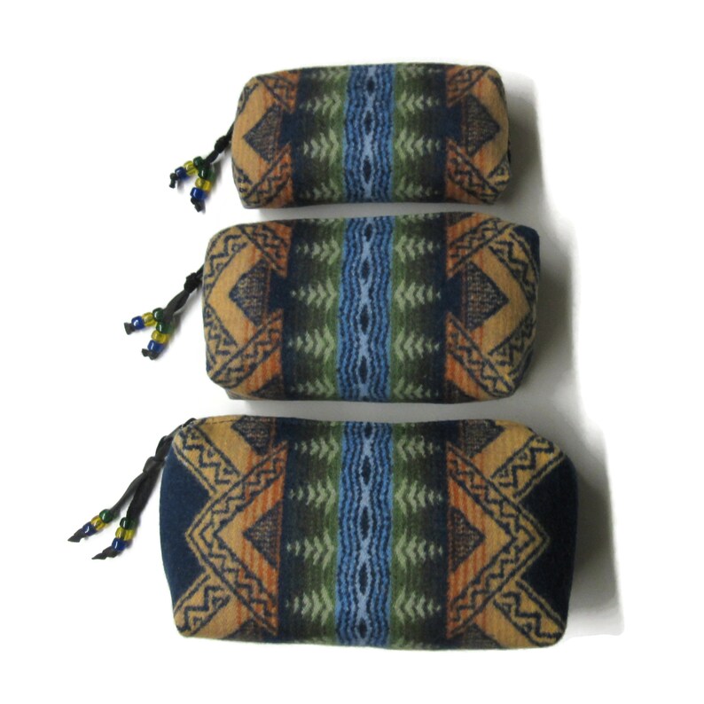 May include: Three cylindrical fabric pouches with a geometric pattern in shades of blue, green, orange, and brown. The pouches have a drawstring closure and are decorated with beads.