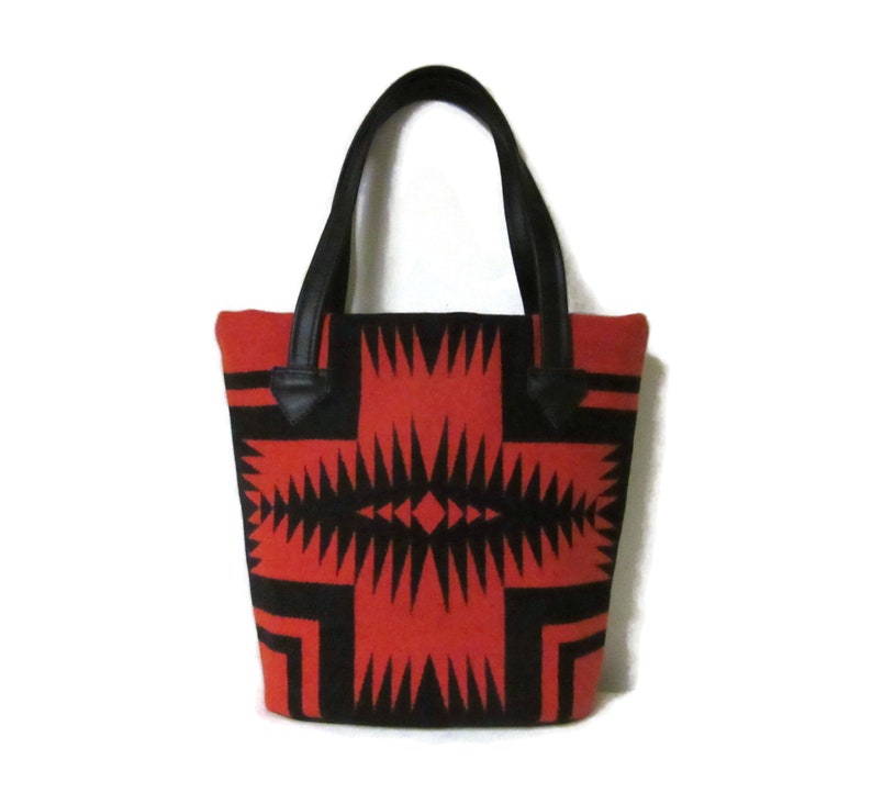 May include: A red and black tote bag with a geometric pattern. The bag has black leather handles.