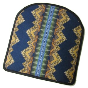 May include: A navy blue seat cushion with a geometric pattern in yellow, orange, green, and blue. The cushion has a black border and a central vertical stripe design. The overall shape is rounded at the top.
