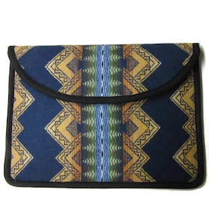 May include: A rectangular, navy blue laptop sleeve with a flap closure. The sleeve features a geometric pattern in shades of gold, orange, green, and blue. The edges are trimmed with black piping, creating a clean, finished look.