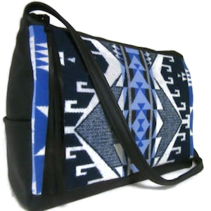 May include: A black shoulder bag with a geometric pattern in shades of blue, white, and gray. The bag has a black strap and a side pocket. The pattern features triangles and other shapes.