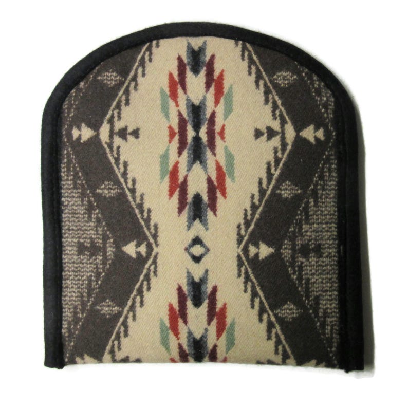 May include: A decorative, arched-top cushion cover with a Southwestern geometric pattern. The design features a central diamond shape with red, blue, and green accents on a cream background. The border is dark brown with a black trim.