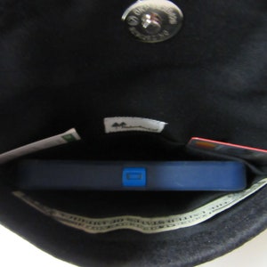 May include: The inside of a black purse with a silver snap closure. The purse contains a blue fitness tracker, a credit card, a piece of paper with the words "Save 10%" and a small tag with the word "Mountain" on it.