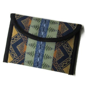 May include: A rectangular, patterned clutch with a black border. The fabric features a geometric design in shades of blue, yellow, and green. The flap is curved, and the clutch appears to be made of a soft material.