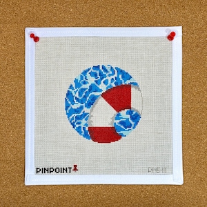 May include: A white canvas with a blue and red life preserver design. The design is surrounded by a white border and the words "PINPOINT II" are printed in the bottom left corner.