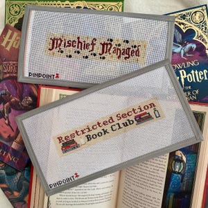 May include: Two gray fabric bookmarks with white embroidery. The top bookmark reads "Mischief Managed" and the bottom bookmark reads "Restricted Section Book Club".