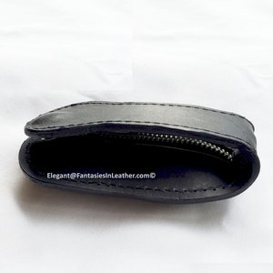 May include: Black leather coin purse with a zipper closure. The purse is open, revealing the interior. The text "Elegant@FantasiesInLeather.com" is visible on the bottom of the image.