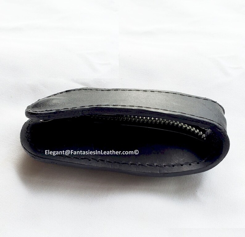 May include: Black leather coin purse with a zipper closure. The purse is open, revealing the interior. The text "Elegant@FantasiesInLeather.com" is visible on the bottom of the image.