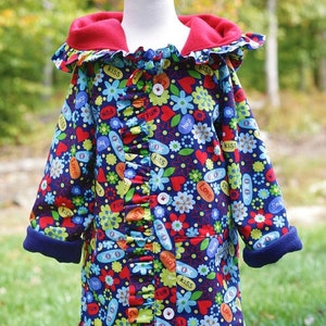 May include: A blue hooded jacket with a red fleece lining and a ruffle trim. The jacket is covered in a colorful print of flowers, hearts, and words like "kiss", "hugs", and "fun".
