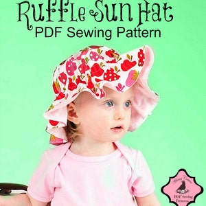 May include: A pink and white sun hat with a ruffle trim and a strawberry print. The hat is being worn by a young child. The text "Ruffle Sun Hat PDF Sewing Pattern" is at the top of the image.
