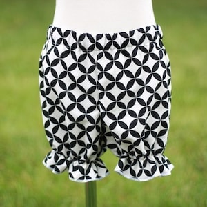 May include: Black and white geometric print baby bloomers with a ruffled hem.