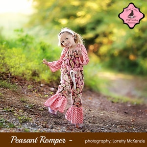 May include: A young girl wearing a pink and brown peasant romper with a white sash and a white headband. The romper has a ruffled hem and a paisley print. The girl is standing on a dirt path in a forest setting. The image includes the text "Peasant Romper - photography: Loretty McKenzie".