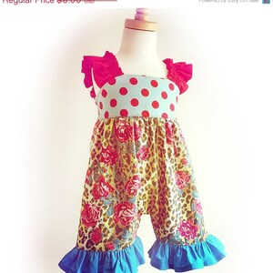 May include: A sleeveless, floral print romper with red polka dot and red ruffle details. The romper has blue ruffles at the bottom.