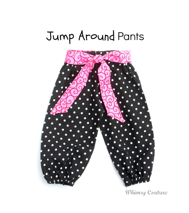 May include: Black and white polka dot pants with a pink and red patterned fabric belt. The pants have a gathered elastic waistband and are labeled "Jump Around Pants".