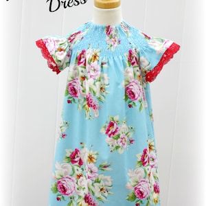 May include: A light blue dress with a floral print and red lace trim. The dress has a smocked bodice and short sleeves. The dress is labeled "Heirloom Garden Dress".