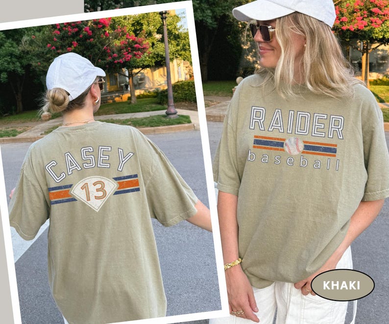 May include: Khaki-colored t-shirts with baseball-themed graphics. One shirt features "RAIDER baseball" with a baseball graphic. The other shirt displays "CASEY 13" with a baseball-style design. Both shirts have short sleeves and a relaxed fit.