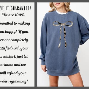 May include: A blue sweatshirt with a large, printed animal print bow on the front. The sweatshirt has a crew neck and long sleeves. The text "LOVE IT GUARANTEE! We are 100% committed to making you happy! If you are not completely satisfied with your sweatshirt, just let us know and we will refund your order right away!" is printed on a white background.
