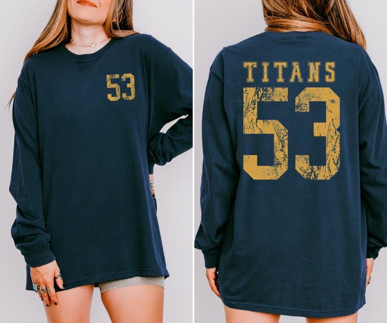 May include: Navy blue long-sleeve shirt with the number "53" in distressed gold on the front and back. The back of the shirt also features the word "TITANS" above the number. The shirt is a comfortable, casual style.