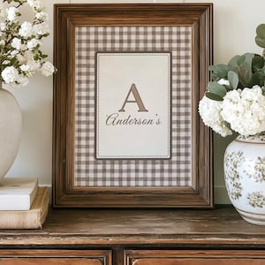 Puede incluir: Un marco con un estampado de cuadros marrones y blancos. El estampado tiene un diseño rectangular central con la letra "A" y el nombre "Anderson's" en escritura marrón. El marco es de color marrón oscuro.