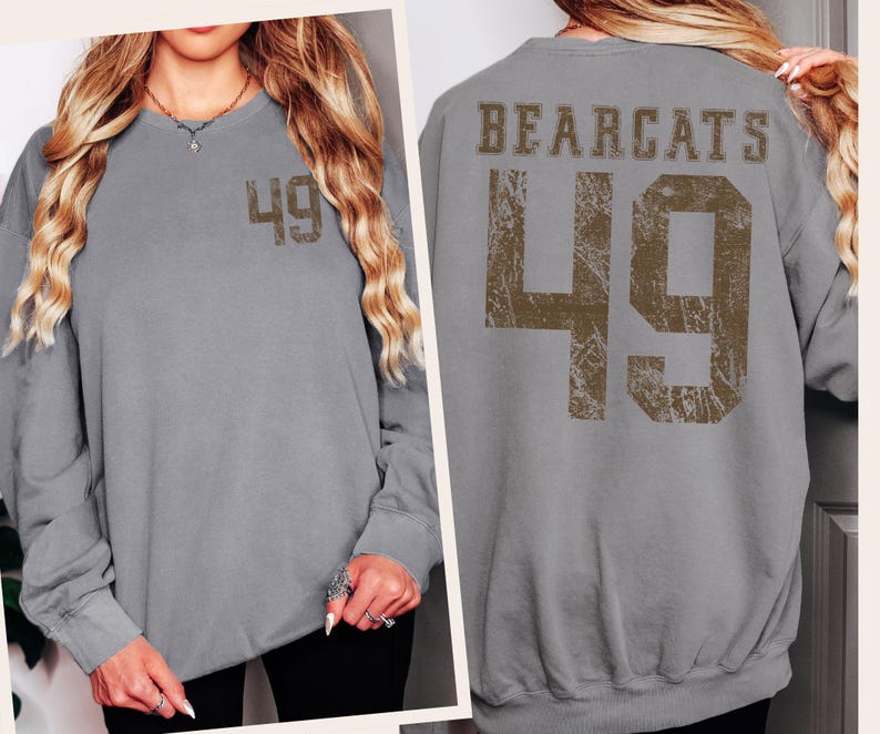 May include: A gray sweatshirt with the number 49 printed on the front and back. The back of the sweatshirt also features the word "BEARCATS" above the number. The number and text are in a distressed, brown font.