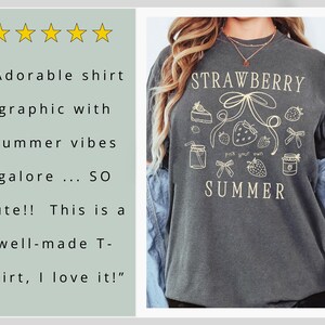 May include: Dark gray t-shirt with a cream-colored graphic that says "STRAWBERRY SUMMER" with strawberry and bow illustrations. The shirt also has the text "pick your own".