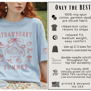 May include: Light blue t-shirt with a strawberry and summer graphic. The shirt features the text "STRAWBERRY SUMMER" in red, along with strawberry illustrations. Made with eco-friendly US cotton and designed in the USA.