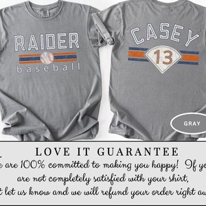 May include: Gray baseball t-shirt with "RAIDER baseball" printed on the front, featuring a baseball graphic. The back of the shirt displays "CASEY 13". The shirt has a crew neck and short sleeves. The word "GRAY" is printed on the bottom right.
