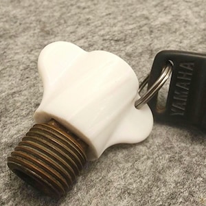 May include: White plastic key cap with a threaded brass stem. The key cap has a YAMAHA key ring attached.
