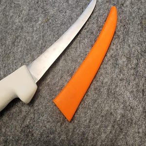 May include: A white handled, curved, stainless steel boning knife with an orange plastic sheath.