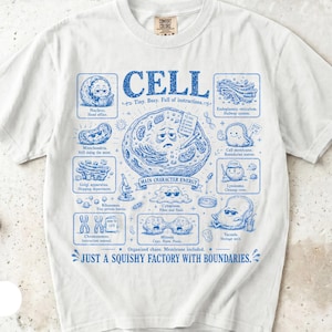 May include: A white short-sleeve t-shirt featuring a blue graphic print of a biological cell diagram. The design includes various cell organelles with cartoon faces and text labels like CELL, Tiny, Busy, Full of instructions, and JUST A SQUISHY FACTORY WITH BOUNDARIES.