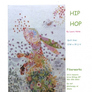 May include: A colourful quilt pattern featuring a floral bunny with the words "Hip Hop" in the top right corner. The quilt is 21 inches wide by 35 inches high. The quilt is made by Laura Heine and is available from Fiberworks.