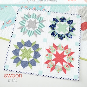 May include: A mini quilt with four starburst blocks in shades of blue, green, gray, and red, set on a white background. The quilt is bordered with a dotted blue fabric and features the text "thimble blossoms" and "swoon #170".