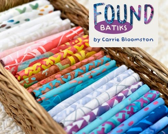 May include: A wicker basket filled with colourful fabric scraps. The fabrics are batik prints with various patterns and colours. The basket is labelled "Found Batiks by Carrie Bloomston".