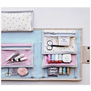 May include: A pink and white fabric folio with multiple pockets and compartments. The folio is open and filled with sewing supplies, including scissors, thread, and needles. The folio is 10 inches by 12 inches.