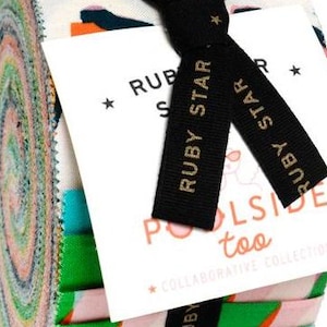 May include: A rolled bundle of patterned fabric strips, secured with a black ribbon. The fabric displays a variety of colours and designs, including green, pink, and blue. A white tag with the text "RUBY STAR" and "Poolside too" is attached.