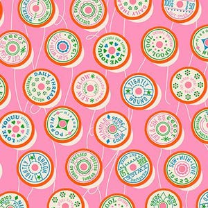 May include: Pink fabric with a repeating pattern of colorful thread spools. Each spool has a white center with text and decorative elements in green, orange, and blue. The words include "Love You", "Sew With Love", and "Tightly Wound".