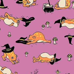 May include: A repeating pattern on a pink background featuring orange frogs wearing black witch hats, with yellow polka dots. The design includes mushrooms, a cauldron, and the text "RUBY STAR SOCIETY".