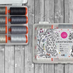 May include: Two clear plastic cases of thread spools. One case contains 12 spools of thread in various shades of gray, black, and white. The other case features a label with two leopard illustrations and the text "GRAYWORK".