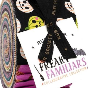 Peut inclure: Un paquet de tissu roulé avec un imprimé sur le thème d'Halloween, avec des têtes de mort et des citrouilles sur fond noir. Le paquet est noué avec un ruban noir et une étiquette "Freaky Familiars Collaborative Collection".