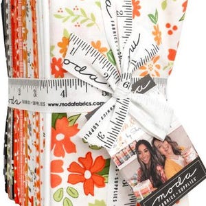 May include: A stack of fabric squares tied with a white ribbon printed with measurements and the words "moda FABRICS + SUPPLIES". The fabric features floral patterns in orange, green, and white. A tag with the "moda FABRICS + SUPPLIES" logo is attached.