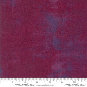 May include: A close-up of a deep burgundy fabric with a subtle blue and purple marbling effect. The fabric has a textured surface and a slightly distressed look.