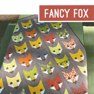 May include: A quilt pattern featuring a design of foxes with different colored fabrics. The pattern is called "Fancy Fox" and is by Elizabeth Hartman. The pattern is for a baby, lap, or twin quilt.