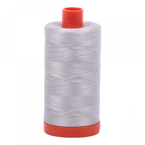 May include: A spool of silver gray thread with an orange plastic bobbin.