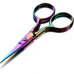 May include: A pair of small, rainbow-colored scissors with a metallic finish. The scissors have a sharp, pointed tip and rounded finger holes. The blades and handles display a vibrant spectrum of colors, including purple, green, and gold.