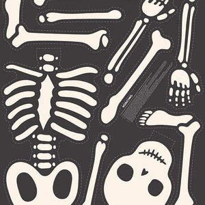 May include: A collection of cream-colored, die-cut skeleton pieces on a dark gray background. The set includes a skull, rib cage, limbs, hands, and feet, all with a stitched outline. The pieces are designed for Halloween or themed crafts.
