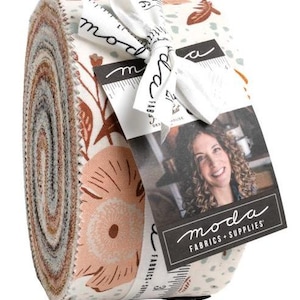 Puede incluir: Un rollo de tela con un diseño floral en tonos melocotón, marrón y crema. Atado con una cinta blanca y una etiqueta que dice "moda FABRICS + SUPPLIES". Ideal para acolchar y coser, la tela es adecuada para diversos proyectos de manualidades.